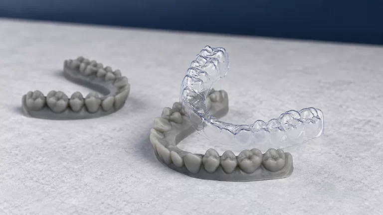 Clear aligner above a grey 3D-printed dental model, illustrating aligner manufacturing workflows